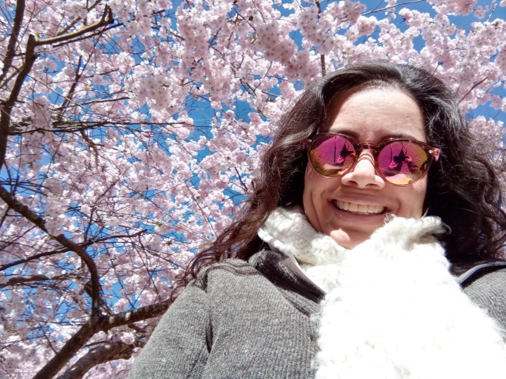 ¿Qué es lo que más desea una persona con alta sensibilidad? Un entorno tranquilo y armonioso.
Descripción de la imagen: Persona sonriendo con gafas oscuras de vidrios rosa con un árbol de cerezo al fondo y un cielo azul despejado.